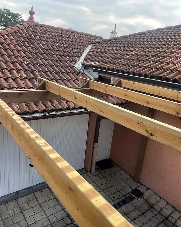 La charpente neuve, entre la maison et le garage. Passage couvert lumineux, chantier de Trois Massifs Toiture.
